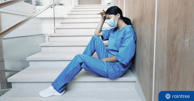 A healthcare clinician sits down in a stairway, looking fatigued and wearing a surgical mask. Illustrating the topic of "Provider Relief Updates."