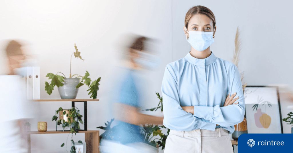 A Financial Professional Stands In A Room Wearing A Surgical Mask. There Are People Walking In The Background, With A Blur Effect To Show Their Movement. Illustrating The Topic: &Quot;Revenue Cycle Management Trends In 2020&Quot;