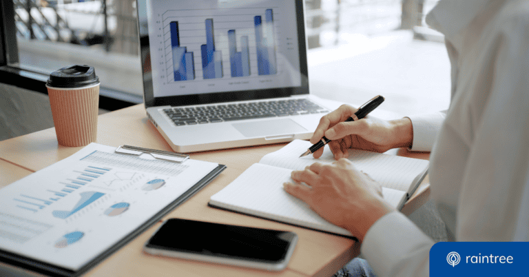 Someone sits at a desk looking at a monitor that displays practice insights in a graph. They're holding a pen and ready to write down notes. Illustrating the topic: "How to Use Your Practice Data with Rehabilitation and Physical Therapy Analytics."