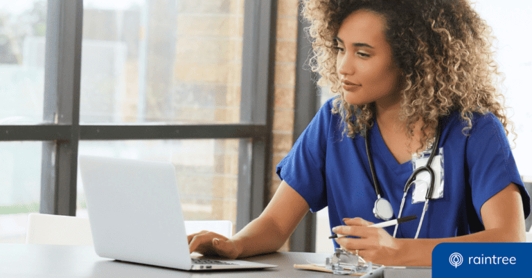 A physical therapist looks down at a computer while wearing blue scrubs. Illustrating the topic: "How to Start a Physical Therapy Blog for Your PT Practice."