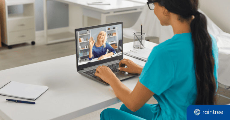 A rehabilitation therapist wearing teal scrubs looks down at a laptop, where a senior patient is on video, smiling. Illustrating the topic: "Telehealth in 2022"