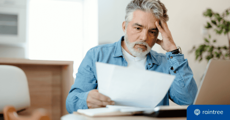 A patient with short gray hair reacts with concern while looking at a medical bill. Illustrating the importance of the No Surprises Act.