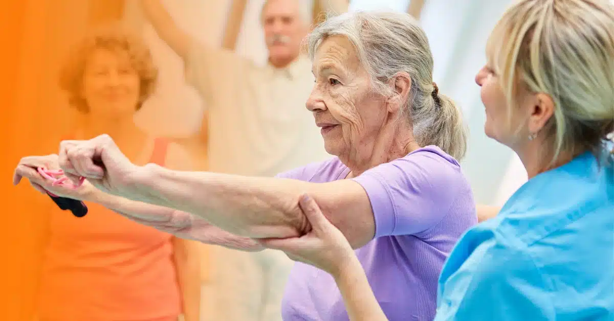 A physical therapist assists a senior patient in a group setting, with two other patients in the background. Illustrating the topic: "Medicare Billing for Group Therapy vs Individual Therapy"