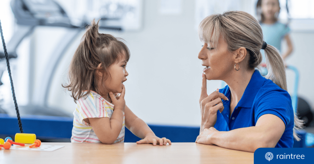 An SLP and a pediatric patient look at one another while touching their bottom lips. Illustrating the topic: Technology in ABA and Speech therapy.