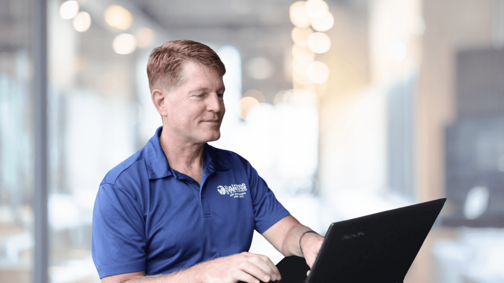 Man In Blue Shirt Using A Computer In An Office Setting