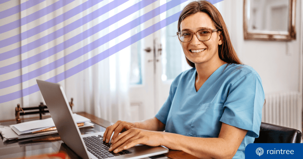 A physical therapist wearing blue scrubs and glasses sits at a desk with her hands resting on a laptop keyboard. She looks at the camera and smiles. Illustrating the topic: "Financial Reports for Physical Therapy and Rehabilitation Practices."