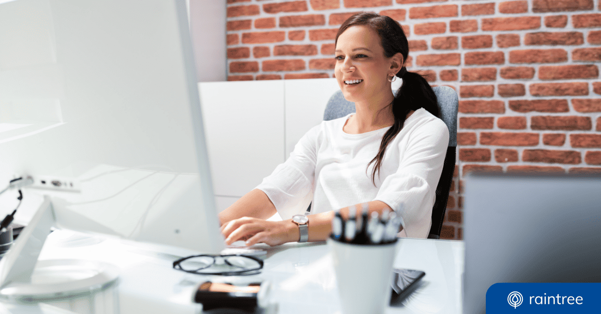 A Healthcare Compliance Officer Sits At A Desk, Looking At A Monitor And Smiling. Illustrating The Topic: &Quot;Mips Lexicon And Terms To Know&Quot;