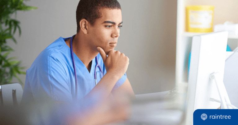 A physical therapist or billing specialist with short hair, wearing blue scrubs, looks at a computer monitor thoughtfully. Illustrating the topic of "The Most Common Codes and Billing Modifiers for PT, OT, and SLP."