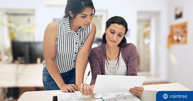 Two compliance team members look at a document while sitting at a desk in the clinic. Illustrating the topic: "Understanding the CMS SAFER Guides Requirements."
