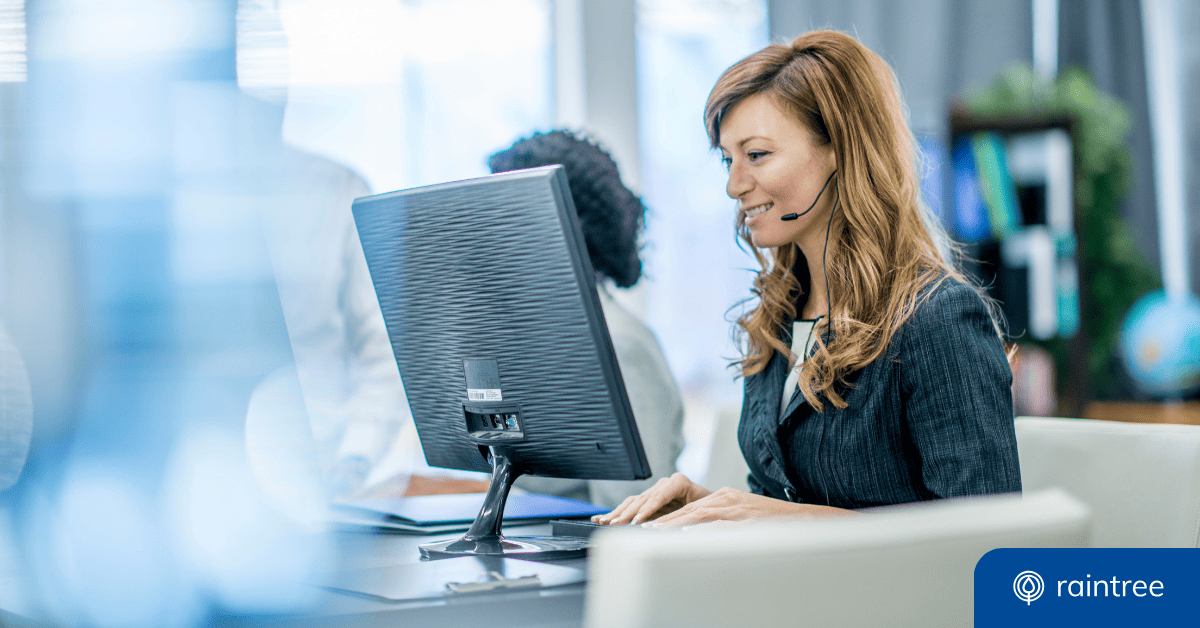 A healthcare administrator with long hair sits at a desktop computer wearing a headset and smiling. Illustrating the topic of healthcare data and AI applications.