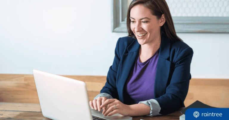 A medical biller wearing a blazer sits at a table and smiles down at a laptop, illustrating the topic of PT billing units and best practices.