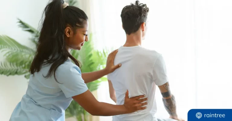 A Physical Therapist With Long Brown Hair Works With A Patient, Who Is Sitting. Illustrating The Topic Of The Provider Credentialing Process.