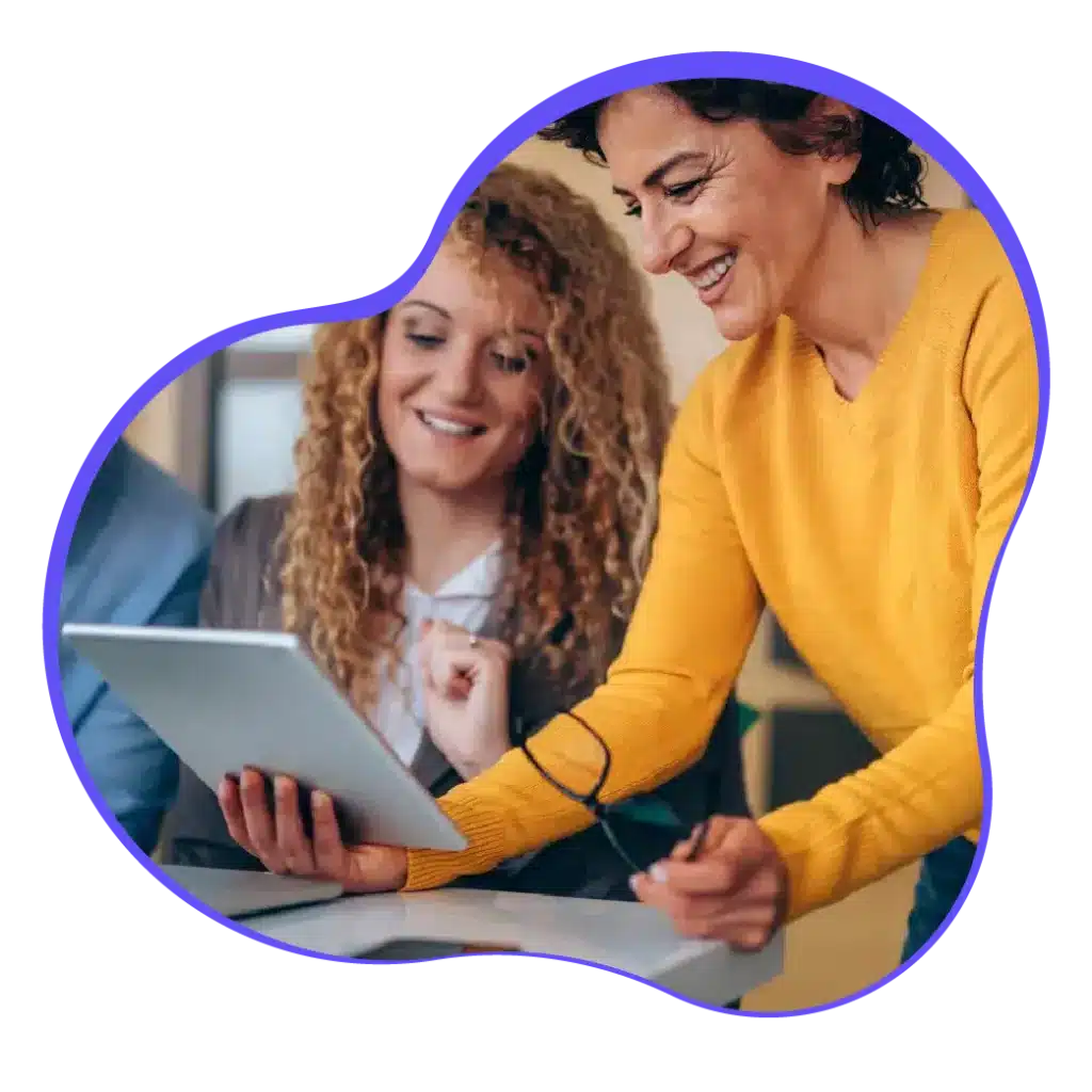 Raintree Partnerships Hero: Two Colleagues Look At A Tablet, Smiling.