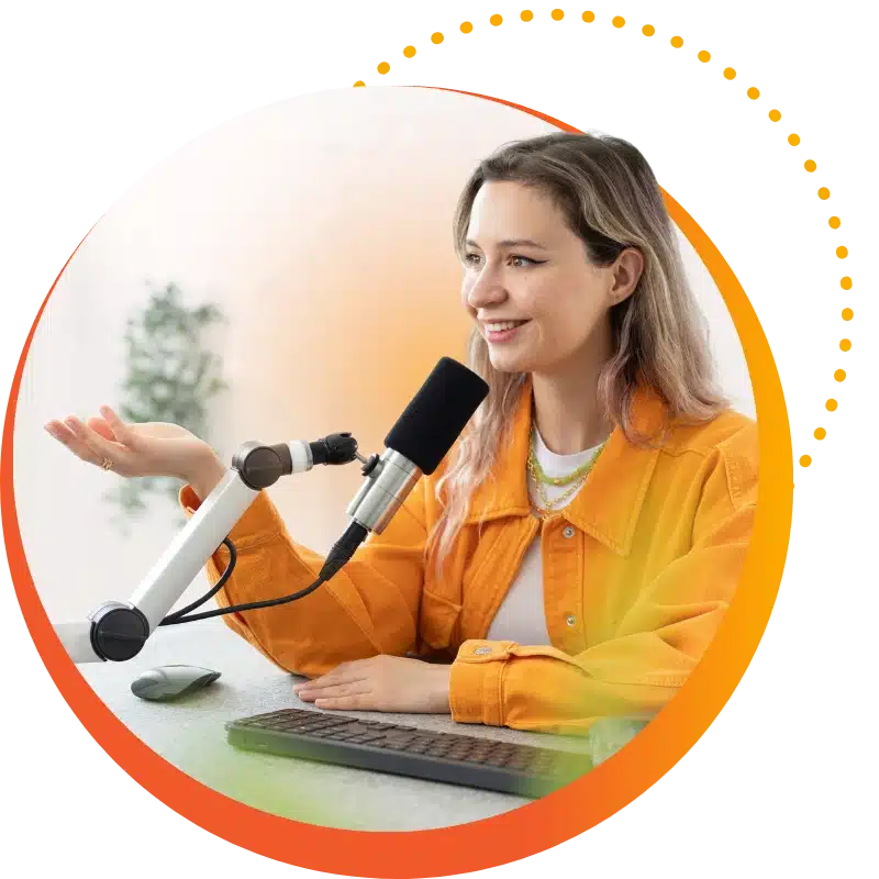 Podcast Hero: A Guest Speaker Wearing A Yellow Jacket Speaks Into A Mic While Smiling.