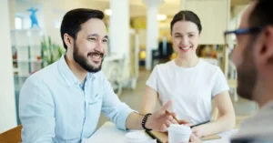 A new provider shakes hands with a credentialing specialist at a physical therapy practice, illustrating the topic of medical credentialing services for rehab therapy.
