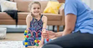 A young child looks up at a BCBA during an applied behavior analysis session, illustrating the topic of reducing turnover in ABA therapy.