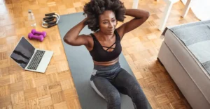 Patient sits on a yoga mat with computer in the background, working on Remote Therapeutic Monitoring program; illustrating the topic of new 2026 RTM Codes for MSK.