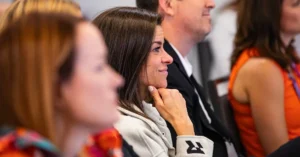 A TherapyCon attendee smiles during a rehab therapy conference session, illustrating the concept of creating a strong business case to attend.